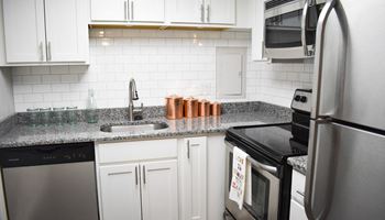 a kitchen with white cabinets and granite countertops